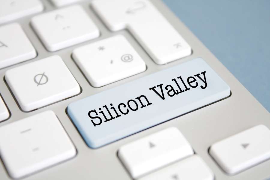 Gros plan sur un clavier d'ordinateur blanc mettant en valeur une touche bleue personnalisée avec l'inscription Silicon Valley.