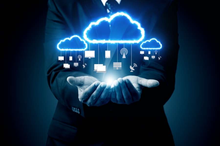 Un homme en costume présente des nuages lumineux connectés à divers appareils, illustrant la gestion et la consommation de données à grande échelle.