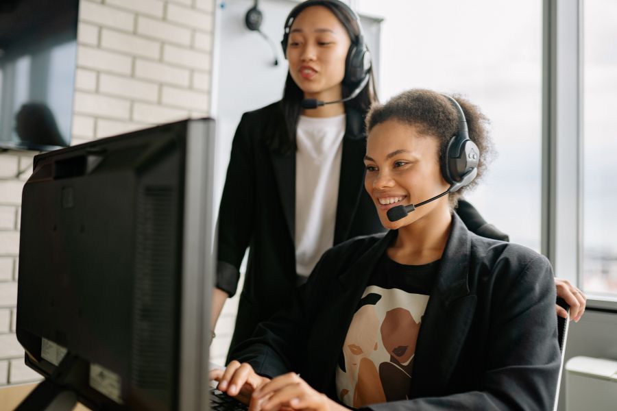 Deux conseillères portant des casques audio collaborent devant un ordinateur pour renforcer l'efficacité des équipes de service client.